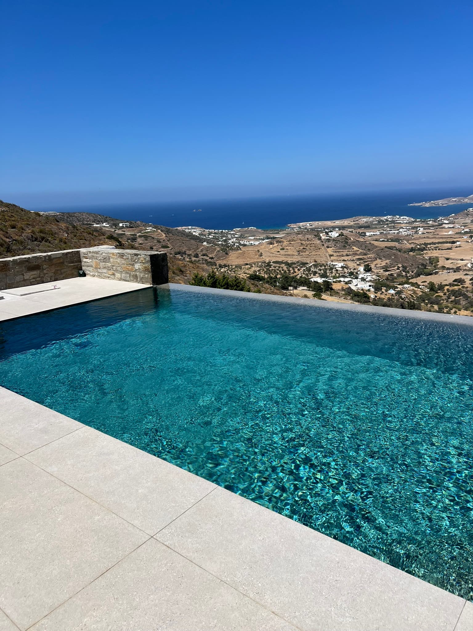 Infinity-edge pool with a clear hillside and sea view at Theasis Paros